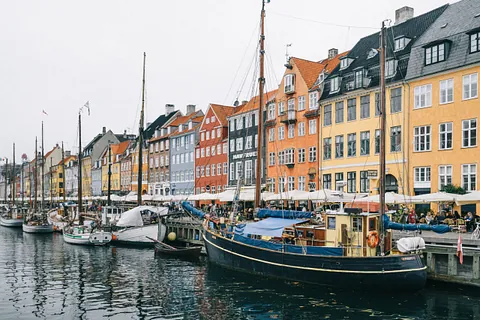 Copenhagon architecture along a costal section with boats in the front.